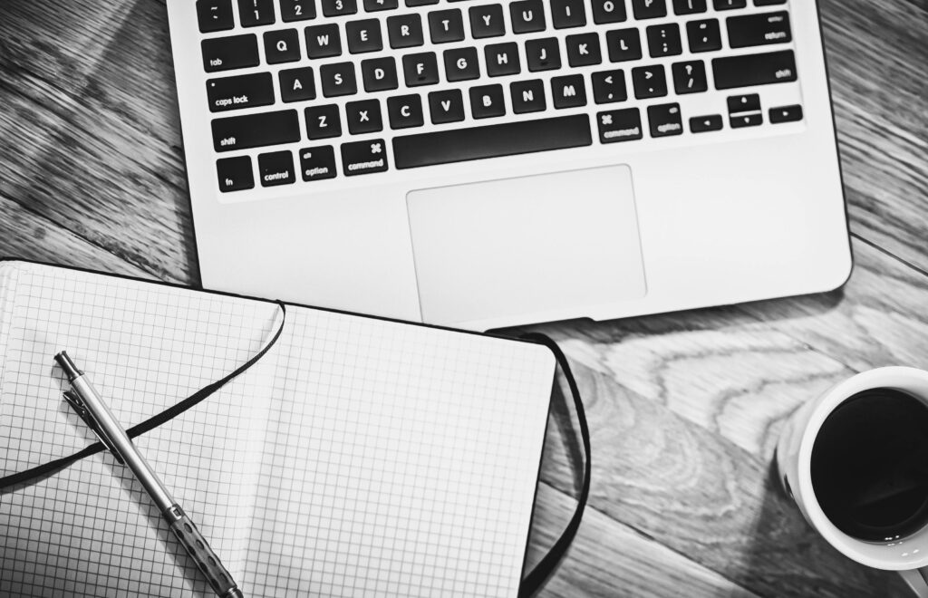 Skuteczny landing page – jak zwiększyć konwersję i przyciągnąć użytkowników Landing page e-commerce – minimalistyczne stanowisko pracy z laptopem, notesem, długopisem i kawą, symbol projektowania strony sprzedażowej.