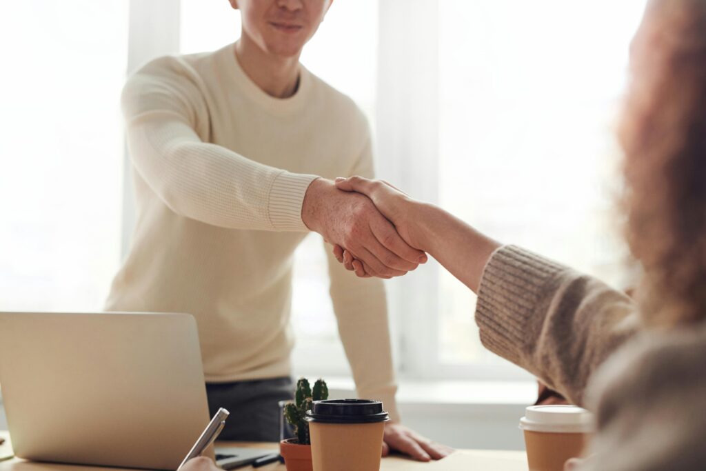 Cobranding – na czym polega i jak wykorzystać go do rozwoju marki Uścisk dłoni podczas spotkania biznesowego przy biurku – cobranding, współpraca marek i wspólne działania marketingowe.